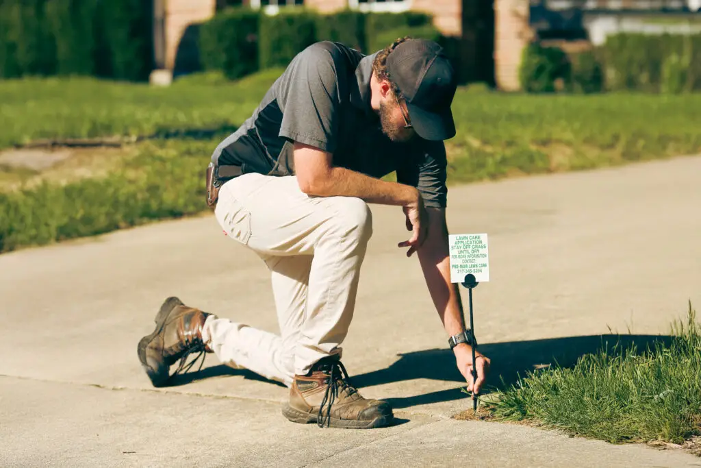 Pro-Mow team member applying lawn fertilizer to a residential lawn